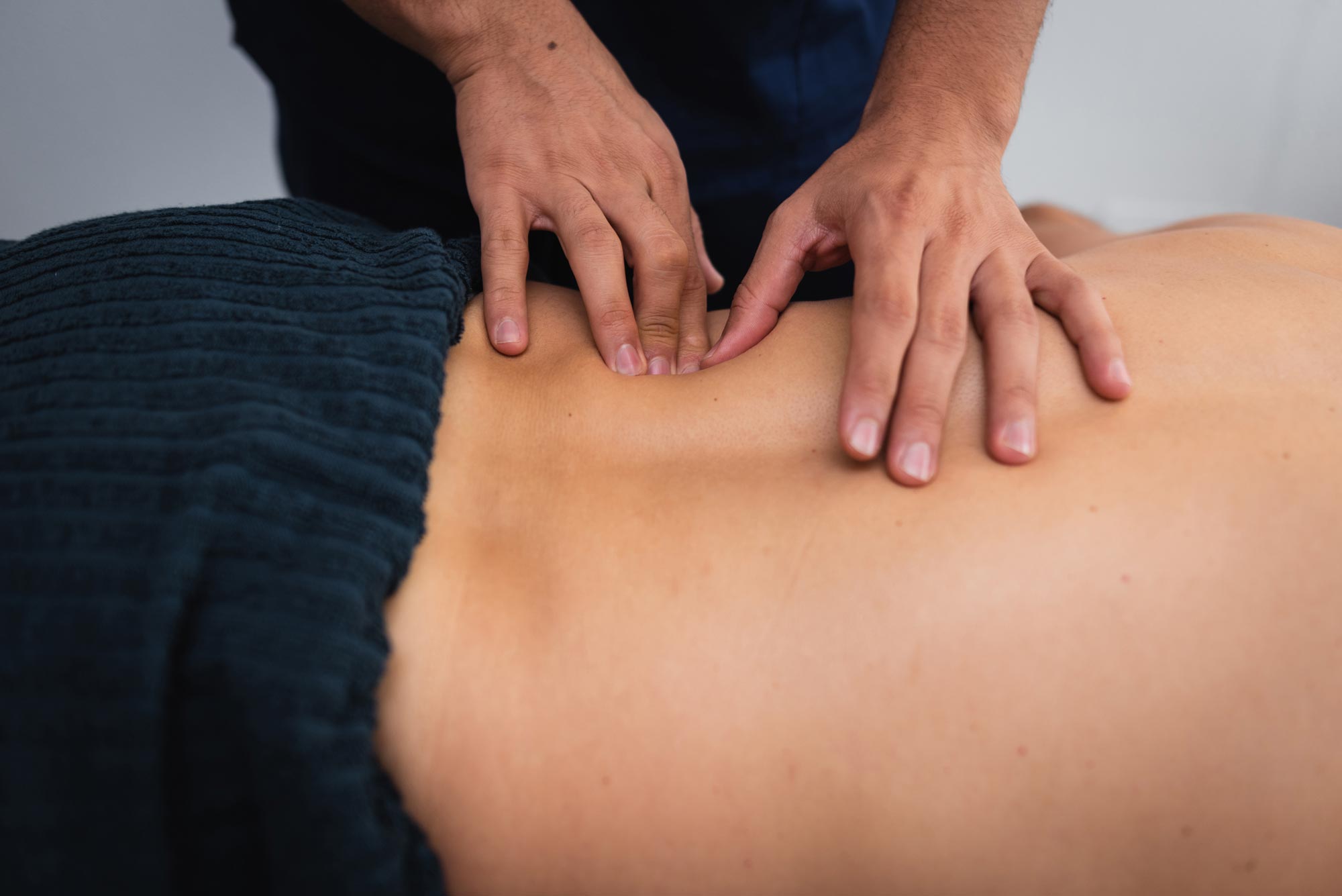 Naprapat utför en ryggbehandling på en patient som ligger på en behandlingsbänk