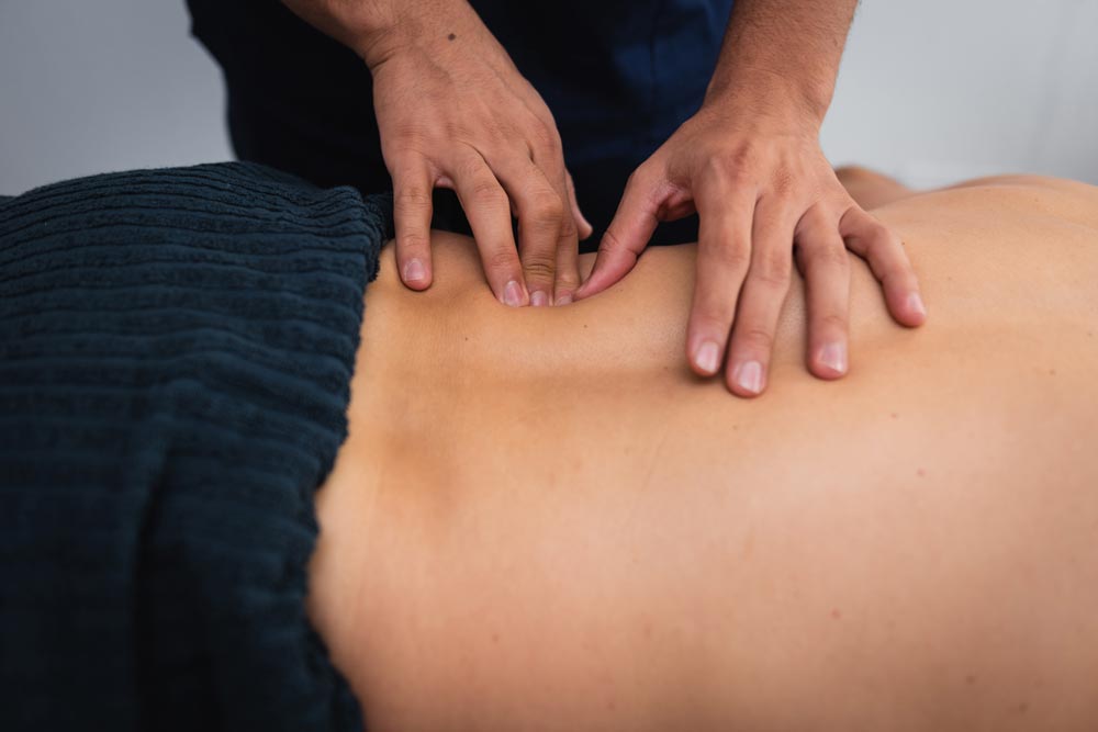 En naprapat utför en ryggbehandling på en patient som ligger på en behandlingsbänk